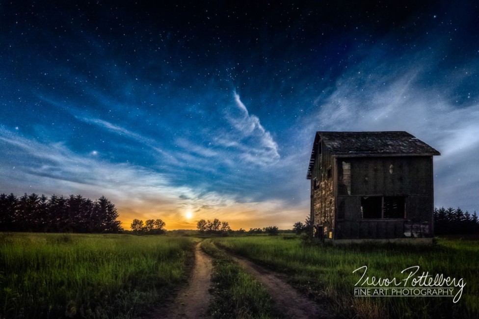 A derelict building on a country lane at sunset
