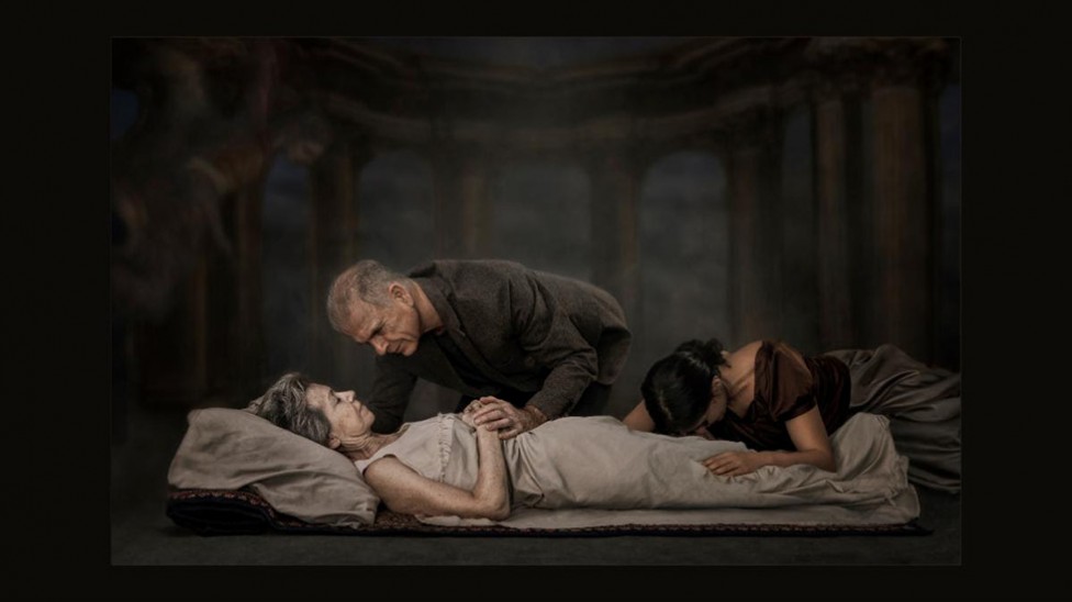 A man and a young woman grieve over a deceased or dying woman's body.