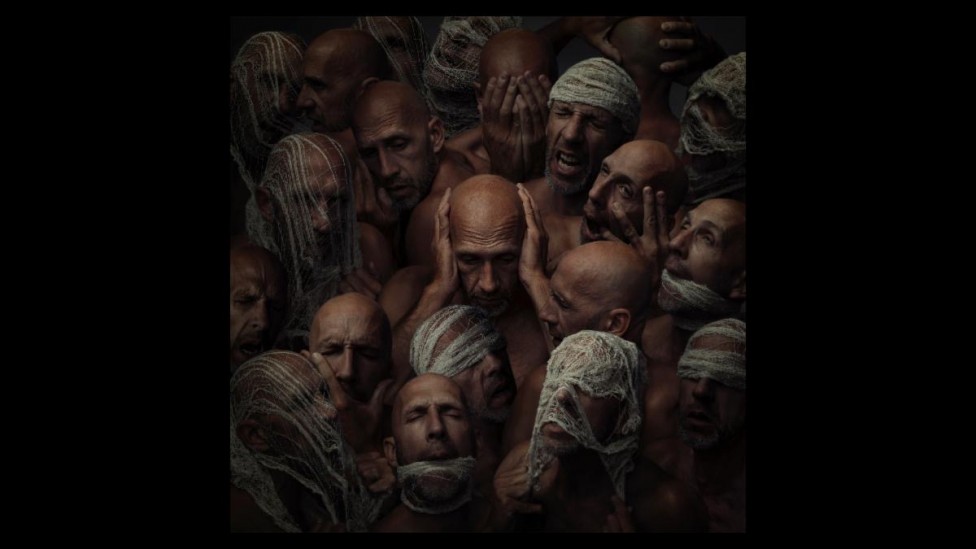 An image of a man surrounded by tormented faces by Victoria West