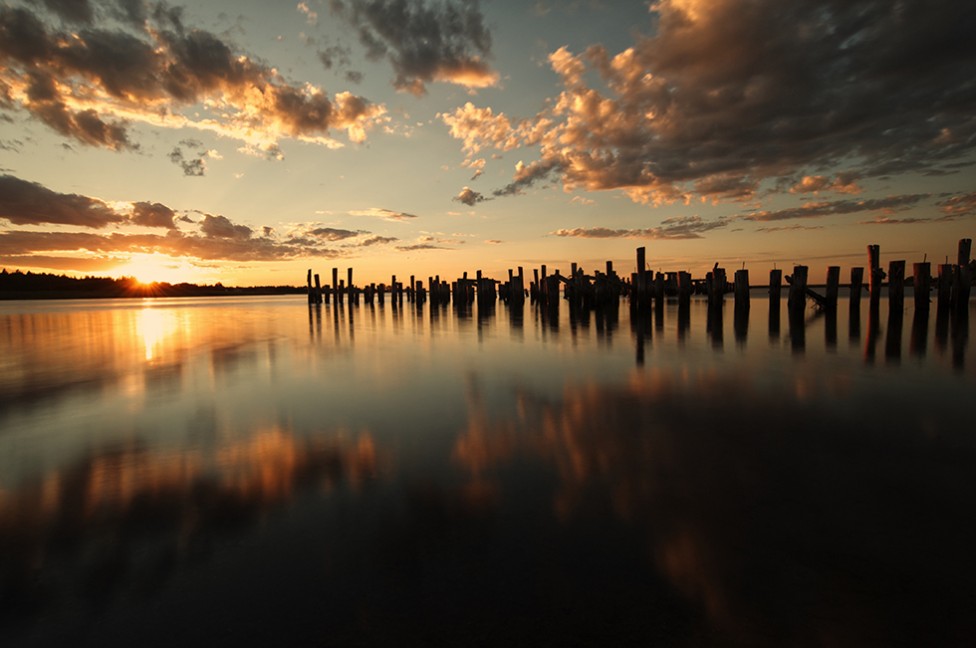 Wooden pilings reflecting in the water at sunset