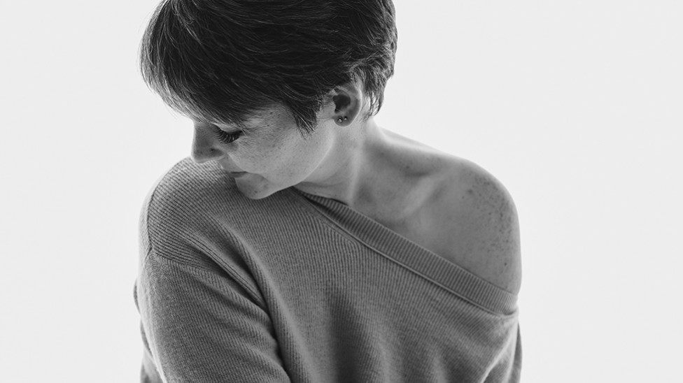 A simple black and white image of a woman wearing an off the shoulder blouse