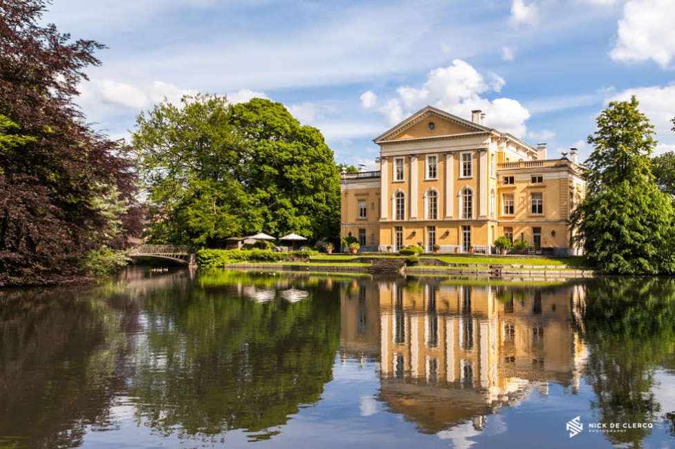 A photo of a castle with pillars reflecting in a lake, by Nick De Clercq