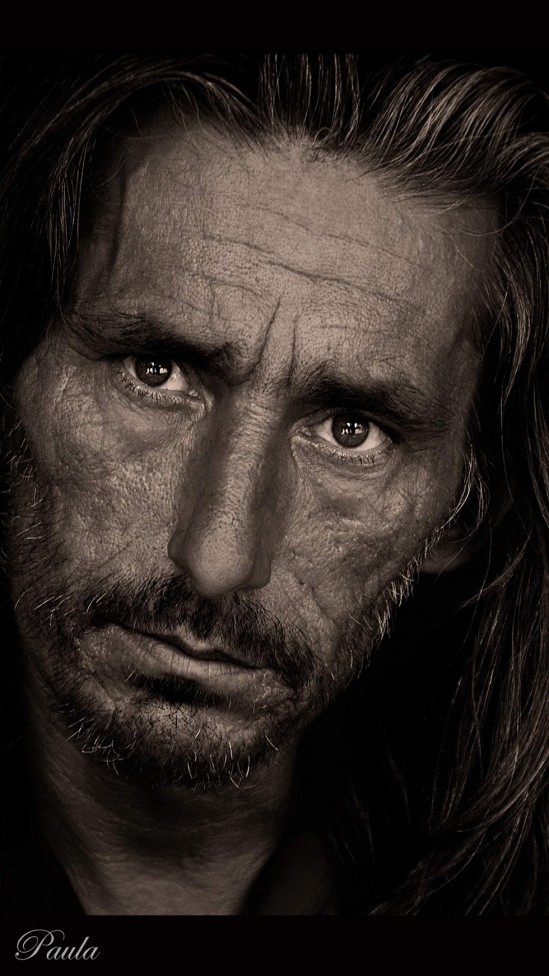A monochrome portrait of a man with a heavily lined face and piercing eyes, by photographer Paula Lirette.