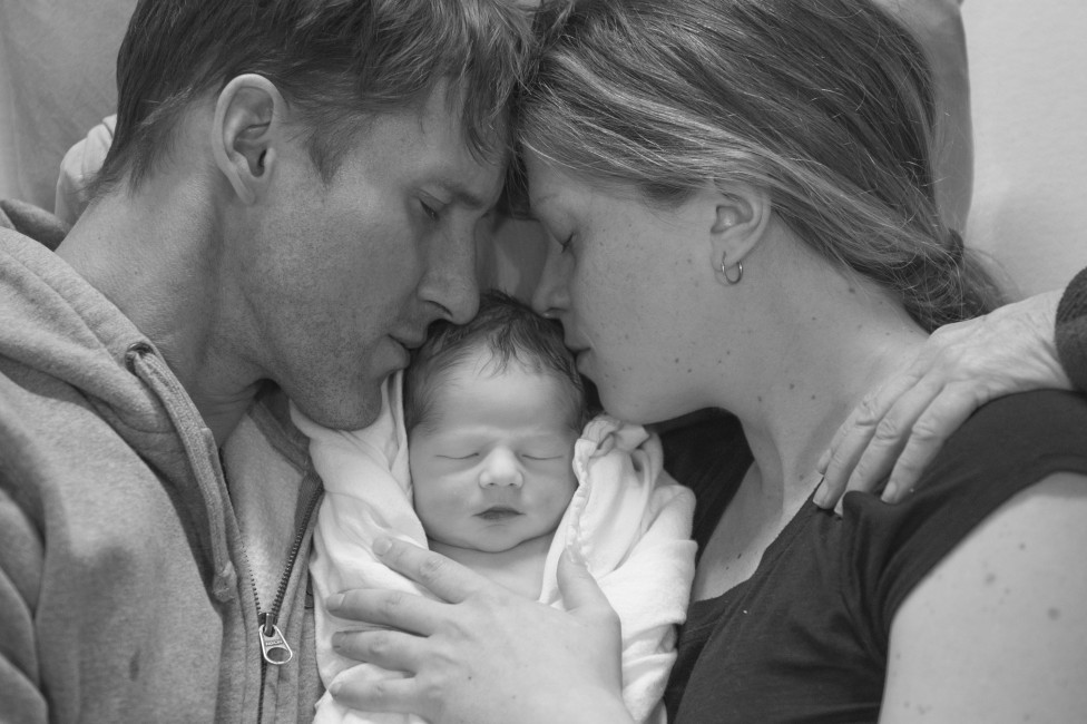 A black and white image of a bereaved couple holding their deceased newborn
